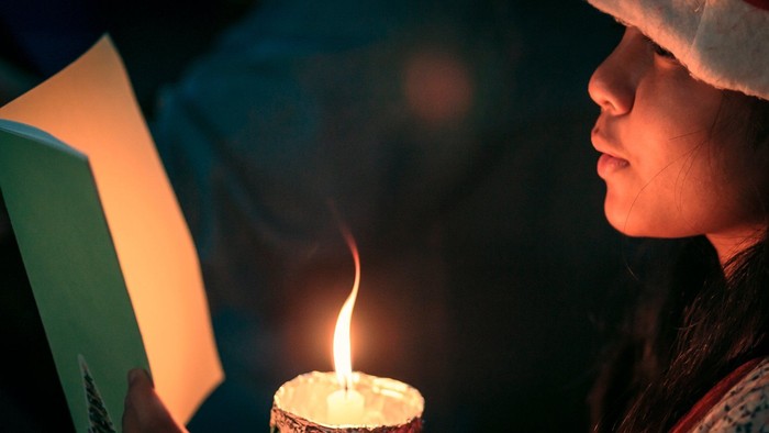 En person læser en bog ved lyset fra en lyse lysestage.