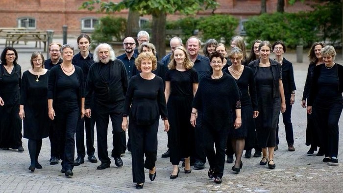 Eine Gruppe von Menschen in schwarzen Kleidern posiert auf einem Kopfsteinpflasterplatz.