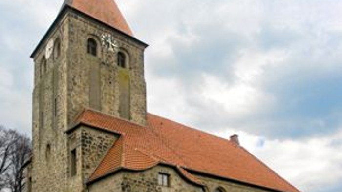 Alte Kirche mit hohem Turm und rotem Dach auf grünem Rasen