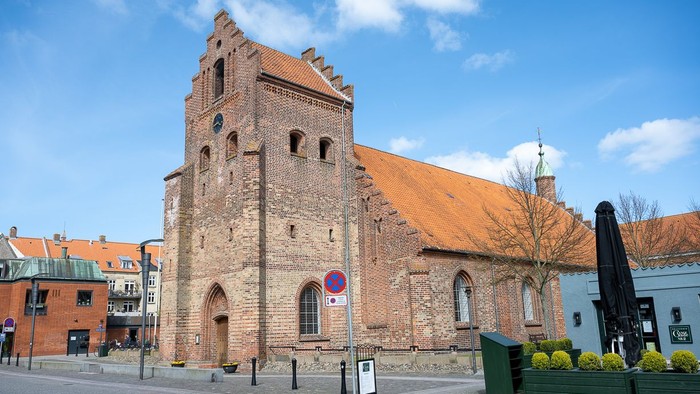 Gamle kirke med teglmur og spistegning i bymiljø
