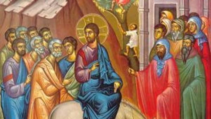 Das Bild zeigt Jesus Christus auf einem Esel, umgeben von einer Gruppe von Menschen, die ihn willkommen heißen.