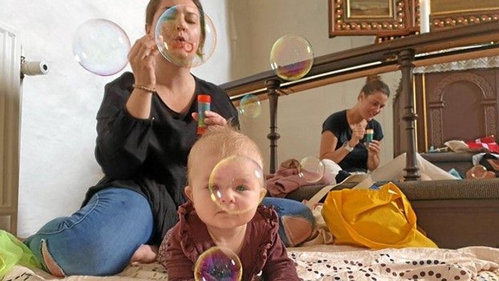 En kvinde og et barn spiller med boblere på en seng