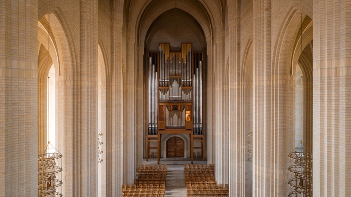 Indre del af en stor kirke med orgel og træbænke.