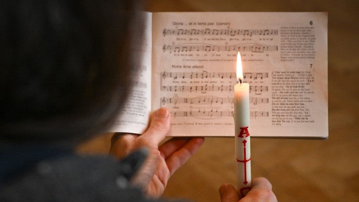 Person hält brennende Kerze über Notenblatt