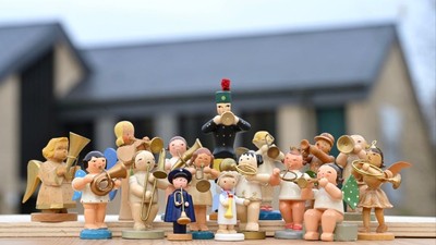 Eine Gruppe von Holzfiguren, die Musikinstrumente spielen, steht vor einem Haus