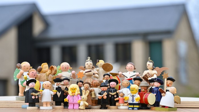 Eine Gruppe von Lego-Minifiguren steht vor einem Haus und spielt Musik