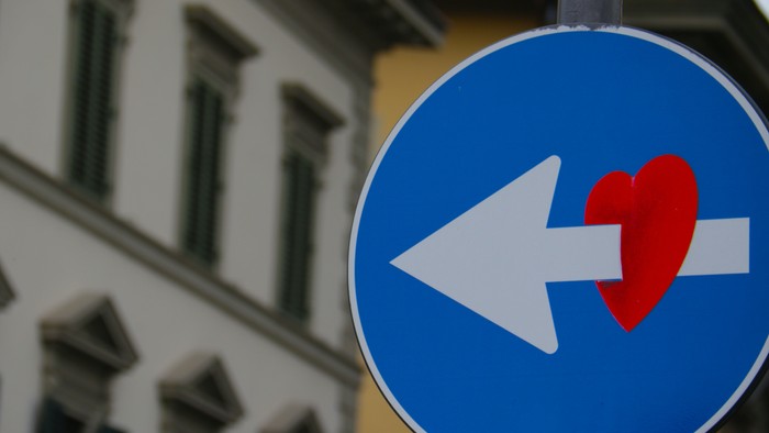 Ein blauer Verkehrsschild mit Pfeil und Herz vor einem Gebäude