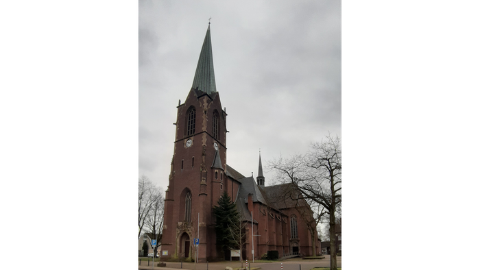 Ein rotes Ziegelkirche mit hohem Turm und Uhr.
