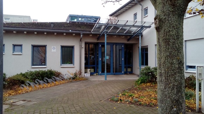 Das Bild zeigt ein modernes Gebäude mit großen Fenstern und Solarpaneelen auf dem Dach.