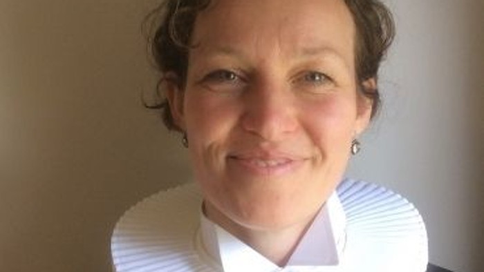 En kvinde med hvid krage og sort blouse.