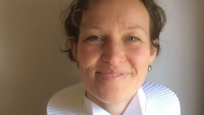 En kvinde med hvid krage og sort blouse.