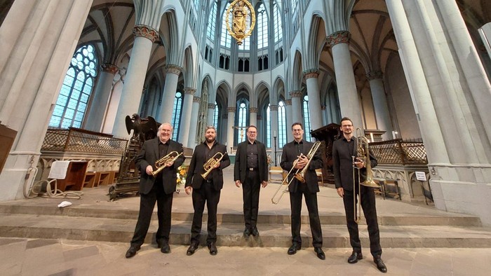 Fünf Musiker posieren in einer Kirche mit Instrumenten