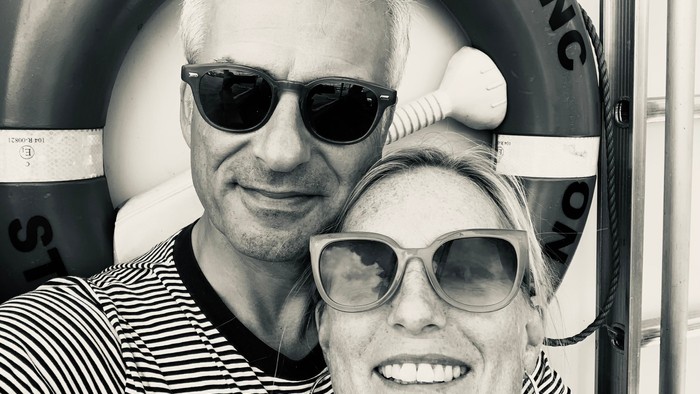 En mand og en kvinde poser med solbriller på en badeplads.