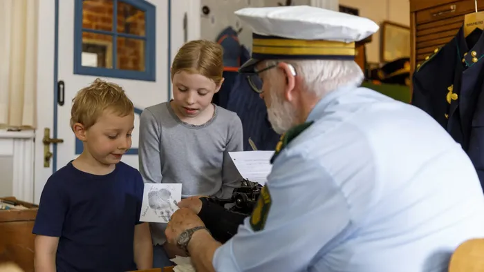 To oldere mænd og to børn ser på en kort.