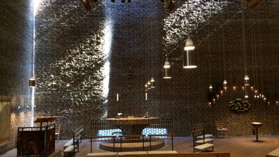 Indre del af en moderne kirke med høje vægge og hængende lys.