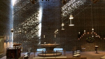 Indre del af en moderne kirke med høje vægge og hængende lys.