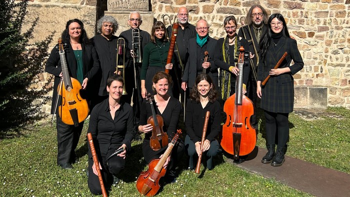 Ein Orchester posiert vor einer alten Steinmauer