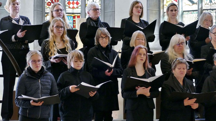 Ein Chor singt in einer Kirche und hält Notenblätter.
