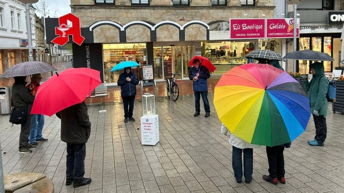 Auf dem Bild sieht man die Gruppe schweigen für den Frieden auf dem oberen Markt in Ibbenbüren. Die Gruppe steht im Kreis, in der Mitte eine Kerze!