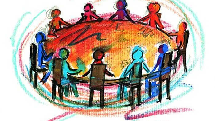 Eine Gruppe von Menschen sitzt im Kreis und hält sich an den Händen.