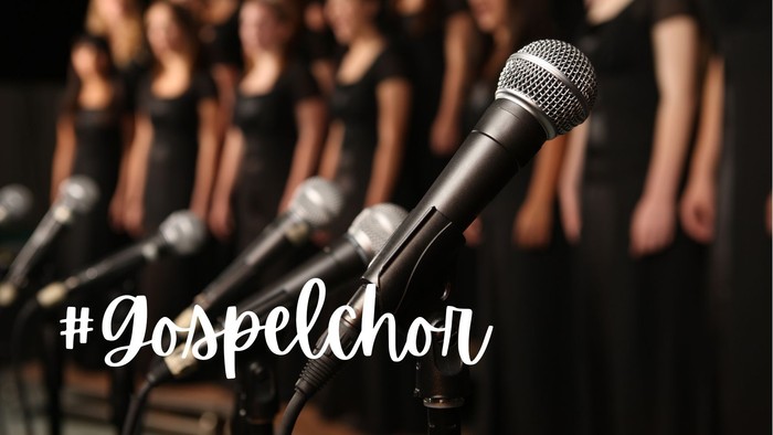 Ein Gospelsänger singt in ein Mikrofon, umgeben von einem Chor.