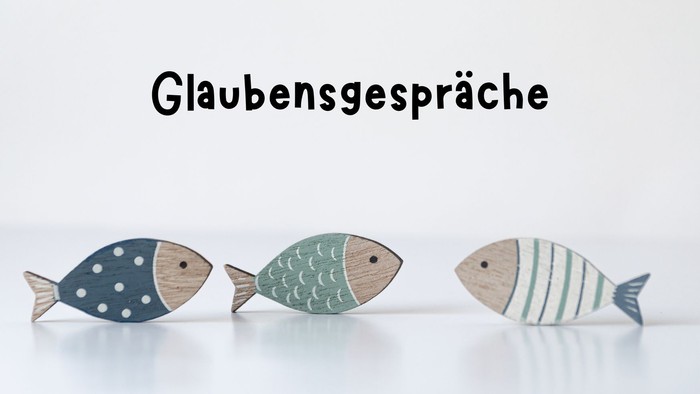 Drei bunte Holzfische stehen auf einer weißen Oberfläche