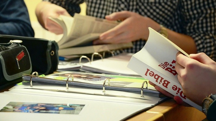 Eine Person blättert in einem Ordner mit Fotos und Dokumenten.