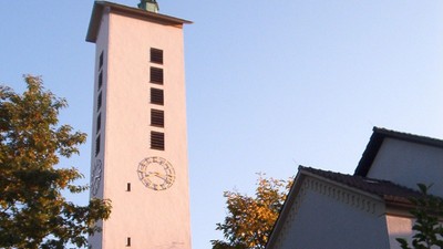 Weiße Kirche mit hohem Turm und Uhr.