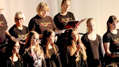 Eine Gruppe von Menschen singt gemeinsam, einige halten Notenblätter