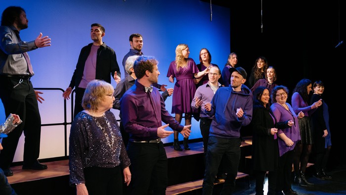 Eine Gruppe von Menschen singt und tanzt auf einer Bühne.