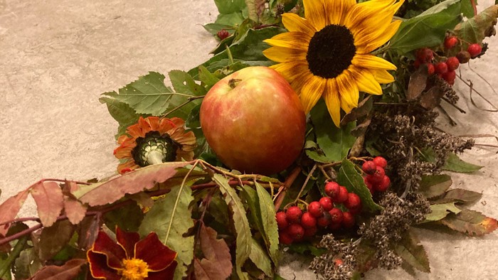 En hesteskede med blomster, blad og en æble