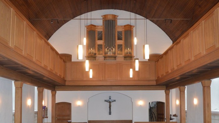 Leere Kirche mit Holzgestühl und roter Teppichbahn