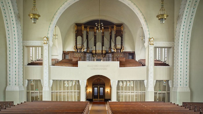 Große leere Kirche mit Holzpulten und Orgel im Hintergrund