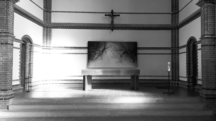 Ein leerer Raum mit einem Kruzifix und einem Bild an der Wand