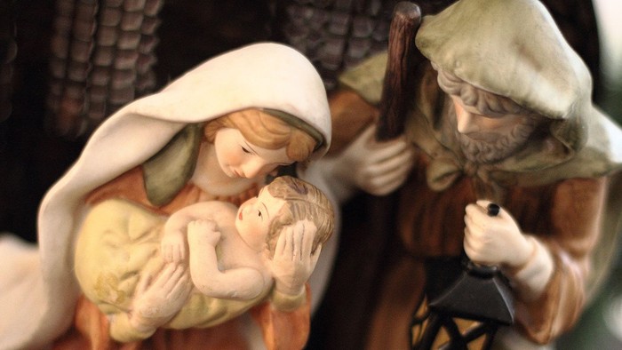 En lille figurine af en kvinde med barn og en mand med lygte.