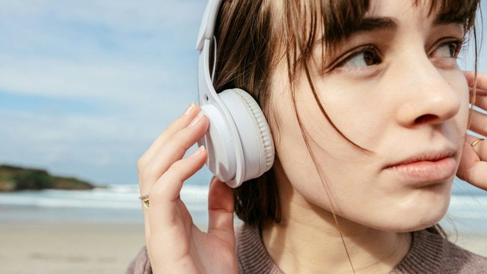 Ein Mädchen mit Kopfhörern am Strand