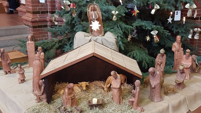 Eine Krippe mit Figuren vor einem geschmückten Weihnachtsbaum