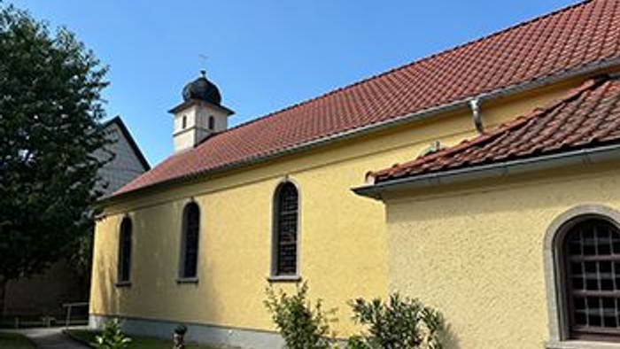 Gelbe Kirche mit rotem Dach und Turm.