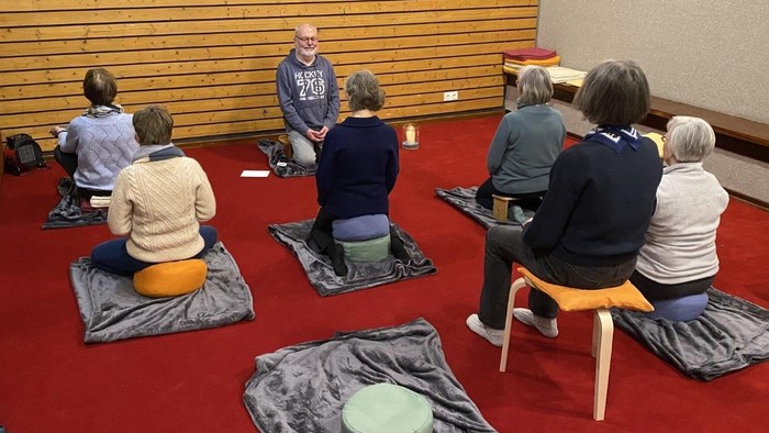 Eine Gruppe von Meditierenden auf einem roten Teppich