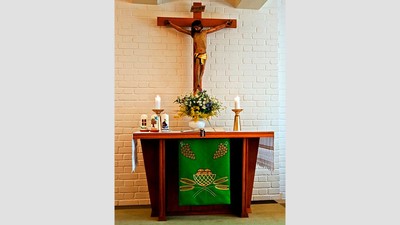 Ein Altar mit Kreuz, Kerzen und Blumen in einer Kirche