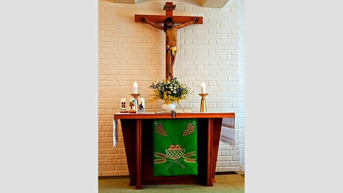 Ein Altar mit Kreuz, Kerzen und Blumen in einer Kirche