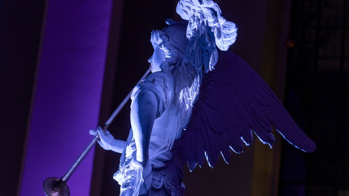 En skuespiller i engelkostume på scene, med vinger og en staf.