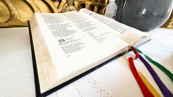 En åben bog med farverne markeret og placeret på en hvid duk ved siden af en keramisk vase