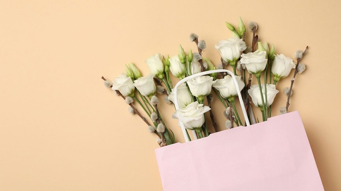 En blomsteraft i rosa papir med hvide roser og lavendel.