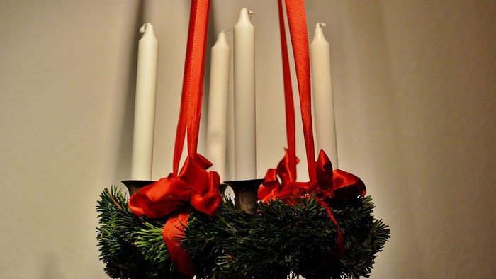 En juledekorasjon med grønne blomster og røde bænder.