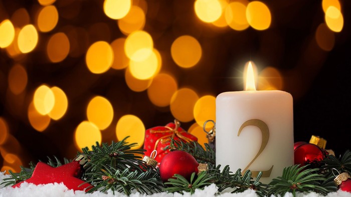 En lysende julelyst med grønne grane og røde kugler foran glitrende lys.