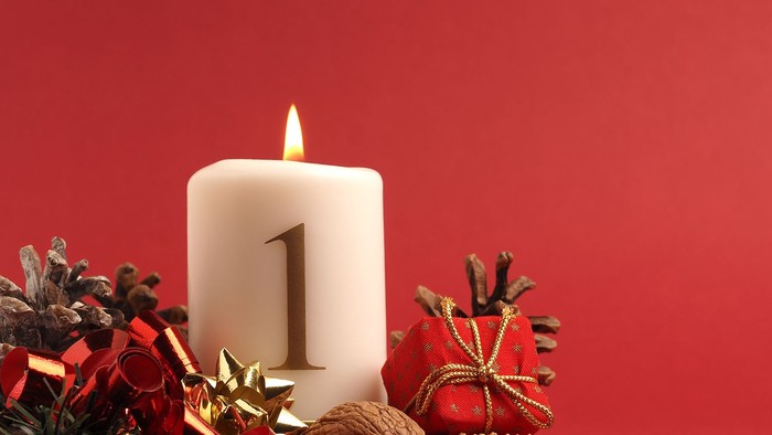 En lysende adventstæppe med tallet 1 omgivet af juleriger og nødder på rød baggrund