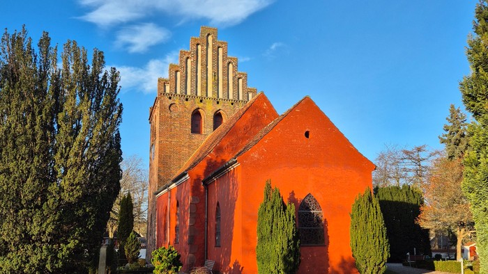 Rødt kirke med spiret og grønne buske foran