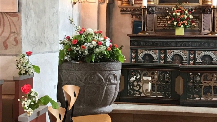 En kirkeinterior med alter, blomster og bænke