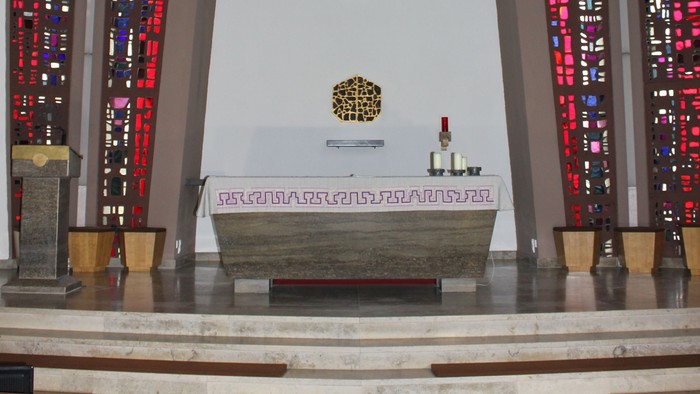 Die Kirche mit Altarraum, Kreuz und buntem Glasfenster